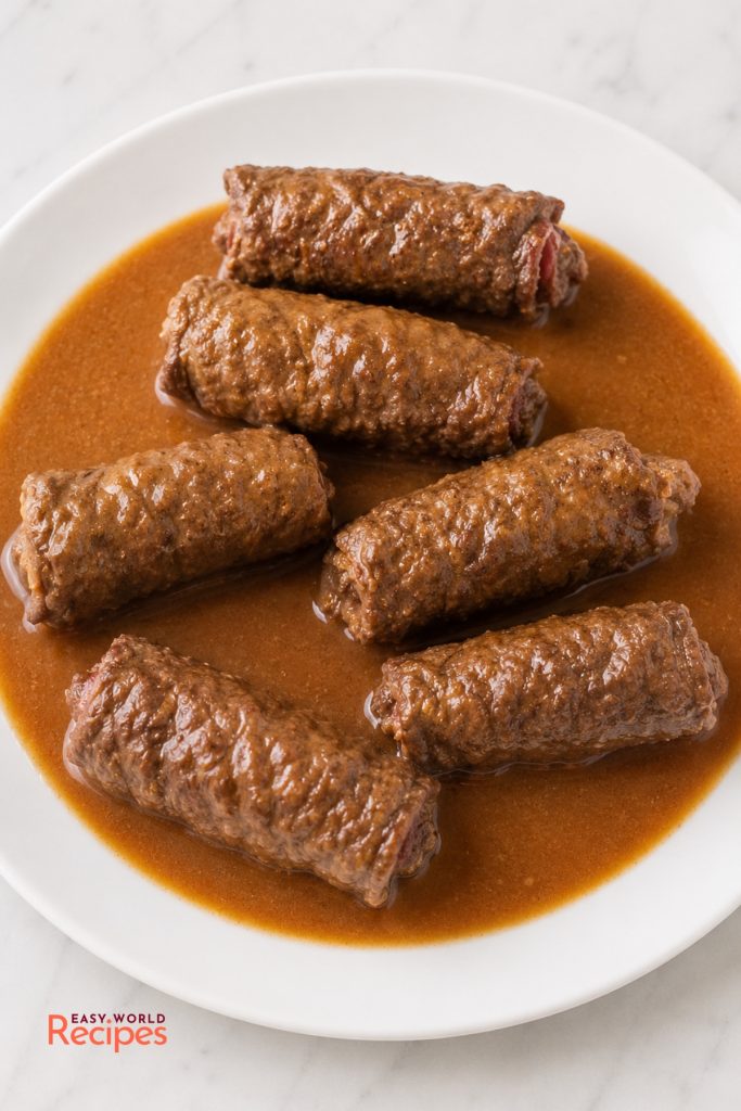 German rouladen served whole with dark gravy, red cabbage, and potato dumplings.