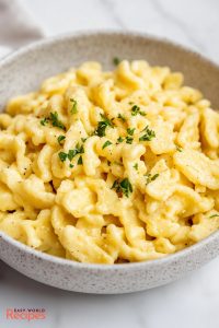 Spaetzle, served in a bowl with melted butter and chopped fresh parsley.