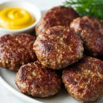 Authentic German Frikadellen, served on a plate with a side of mustard.