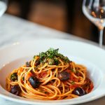 Spaghetti Puttanesca, served on a white plate.