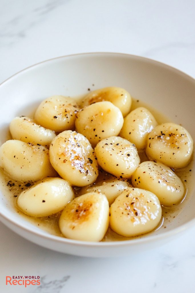 Traditional Italian Homemade Gnocchi, sautéed in butter, served on a plate.