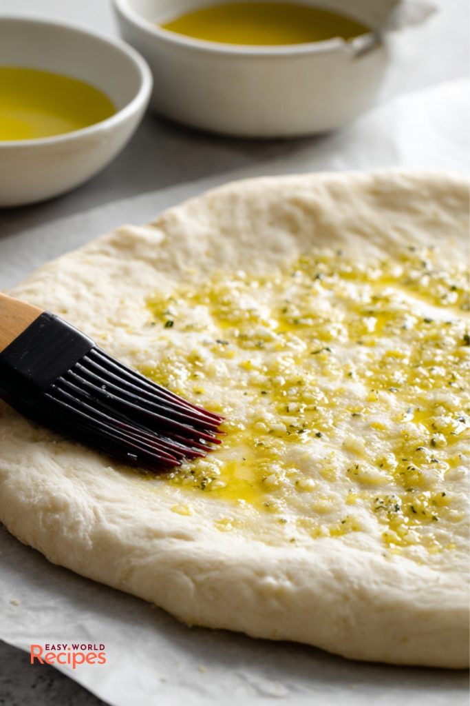 Brushing garlic olive oil onto pizza dough for White Pizza