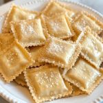 Ricotta Ravioli, sprinkled with parmesan cheese, served on a white plate.