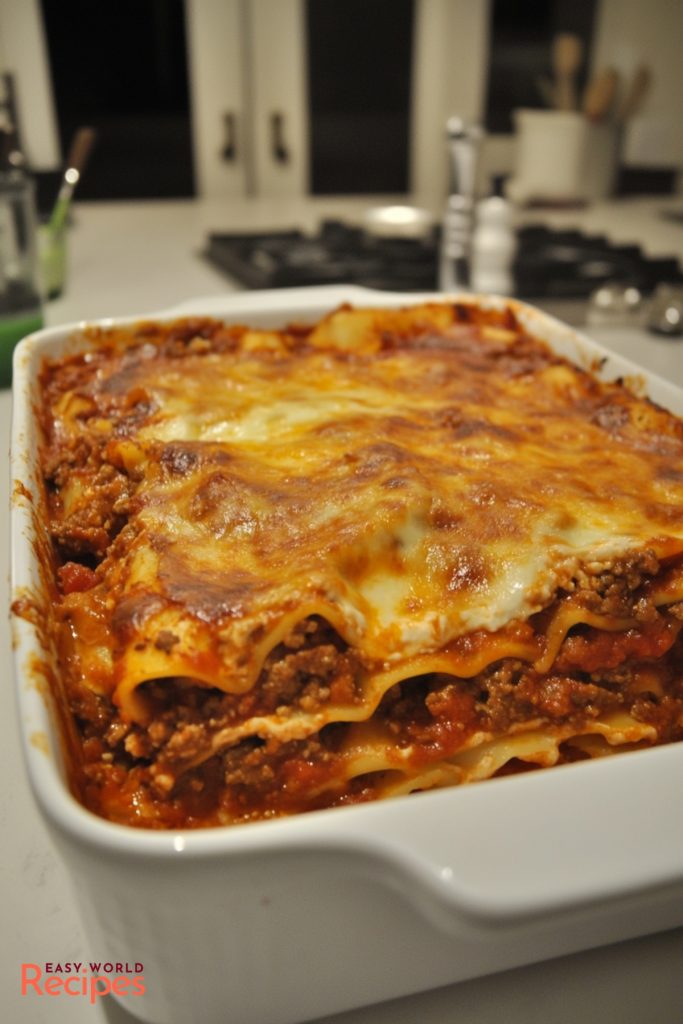 Authentic Lasagne Bolognese served in a large white baking dish, on a kitchen countertop.