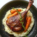French Duck Confit, served with mashed potatoes on a plate.