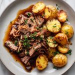 Kleftiko with potatoes, served on a plate.