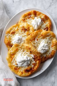 Langos with Classic Toppings, on a white plate.