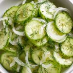 German cucumber salad recipe with glossy cucumber slices, vinegar, oil, thin onion, and dill.
